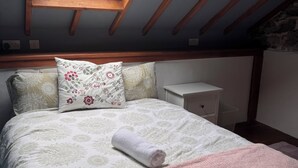 A bedroom with a skylight, a bed with floral bedding, a bedside table, and a nightstand.