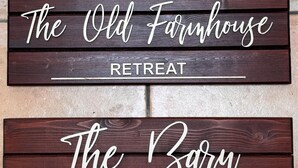 A wooden sign with the text 'The Old Farmhouse Retreat' and 'The Barn' on it.