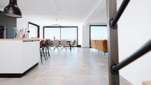 A modern kitchen with a dining area, large windows, and a view of the outdoors. - Villa Bellevue (Donville-les-Bains)