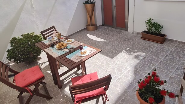 A patio with a table set for two, chairs, potted plants, and a door with a stone archway. - Maria's Heaven House - Old Town Apartment with Private Terrace, Wi-Fi & Air Conditioning (Rodos)