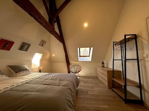 A bedroom with a sloped ceiling, a bed, a chair, a dresser, and a window. - Town house - 8 people (Parthenay)