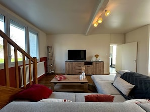 A living room with a sofa, a coffee table, a TV, and a staircase. - Town house - 8 people (Parthenay)