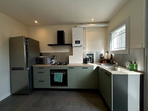 A modern kitchen with stainless steel appliances, a microwave, a stove, and a sink. - Town house - 8 people (Parthenay)