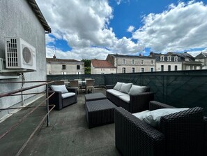A rooftop terrace with wicker furniture, a metal railing, and a view of surrounding buildings. - Town house - 8 people (Parthenay)