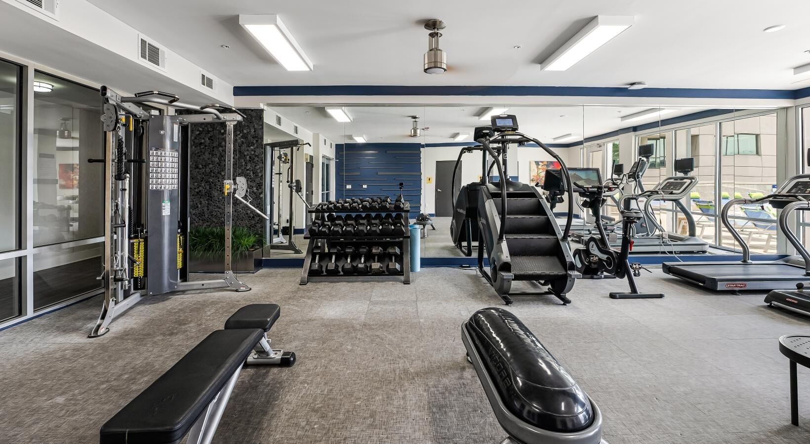 A gym with exercise equipment, benches, and dumbbells.