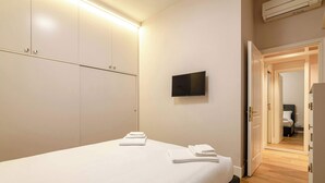 Ein Hotelzimmer mit Bett, einem Flachbildfernseher an der Wand und einem Kleiderschrank mit Spiegel.