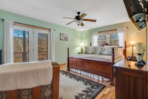 Ein Schlafzimmer mit Bett, Schreibtisch, Stuhl, Deckenventilator und großen Fenstern.