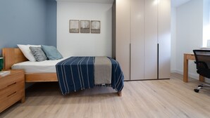 A bedroom with a bed, a desk, a wardrobe, and three framed pictures on the wall. - Lovely 1-bedroom apartment in welcoming Epsom for your stay (Epsom)