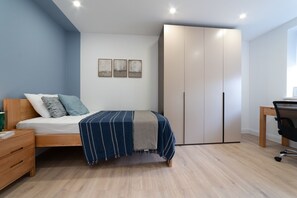 A bedroom with a bed, a desk, a wardrobe, and three framed pictures on the wall. - Lovely 1-bedroom apartment in welcoming Epsom for your stay (Epsom)
