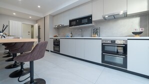 A modern kitchen with a central island, two ovens, a microwave, and a skylight. - Lovely 1-bedroom apartment in welcoming Epsom for your stay (Epsom)