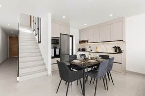 A modern kitchen with a dining area, a staircase, and a built-in oven. - Villa Infinity Views 3 by Escape Home (Tahiche)