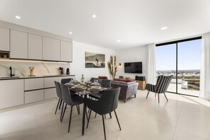A modern living space with a dining area, kitchen, and a large window offering a view. - Villa Infinity Views 3 by Escape Home (Tahiche)