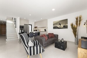 A modern living room with a sofa, a coffee table, and a dining area with chairs. - Villa Infinity Views 3 by Escape Home (Tahiche)