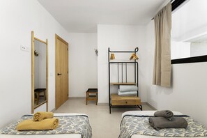 A room with two beds, a wooden wardrobe, a small stool, a metal shelf with towels, and a mirror. - Villa Infinity Views 3 by Escape Home (Tahiche)