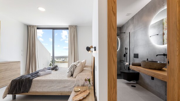 A modern bedroom with a large bed, a wooden bedside table, a nightstand, a bathroom with a large mirror, a sink, and a shower. - Villa Infinity Views 4 by Escape Home (Tahiche)