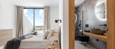 Une chambre moderne avec un grand lit, une table de chevet en bois, une commode, une salle de bain avec un grand miroir, un lavabo et une douche.