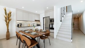 A modern kitchen with white cabinets, a dining table set with plates and glasses, and a staircase with a glass railing. - Villa Infinity Views 4 by Escape Home (Tahiche)