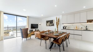 A modern dining area with a large table, chairs, and a view of the cityscape. - Villa Infinity Views 4 by Escape Home (Tahiche)