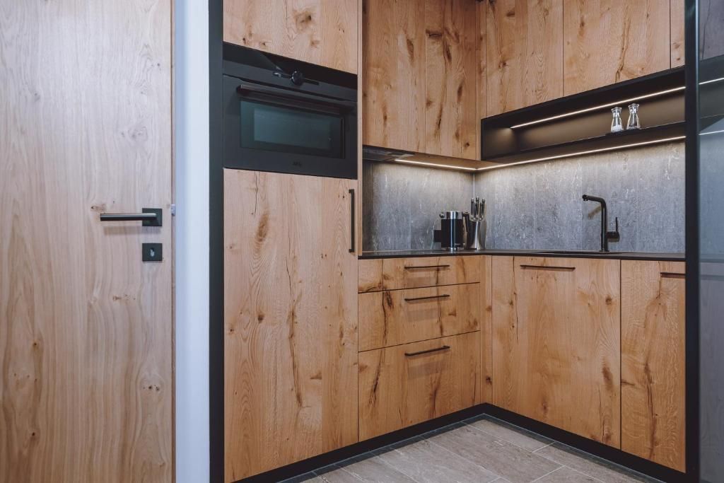 Une cuisine moderne avec des meubles en bois, un four encastré et un plan de travail en acier inoxydable.