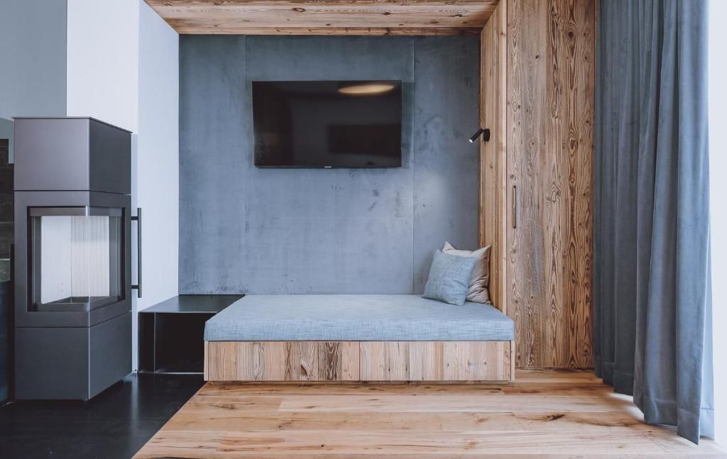 Una habitación moderna con un banco empotrado, un televisor de pantalla plana montado en una pared de concreto y piso de madera.
