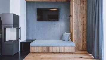 Una habitación moderna con un banco empotrado, un televisor de pantalla plana montado en una pared de concreto y piso de madera.