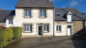 A two-story house with a stone facade, a front door, and a driveway leading to the entrance.