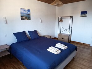 Un dormitorio con una cama grande, dos mesitas de noche, un aparador de madera y una lámpara colgante.