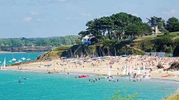 A beach with boats, people, and a building on a hill.