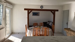 A dining area with a table, chairs, a clock, and a couch.