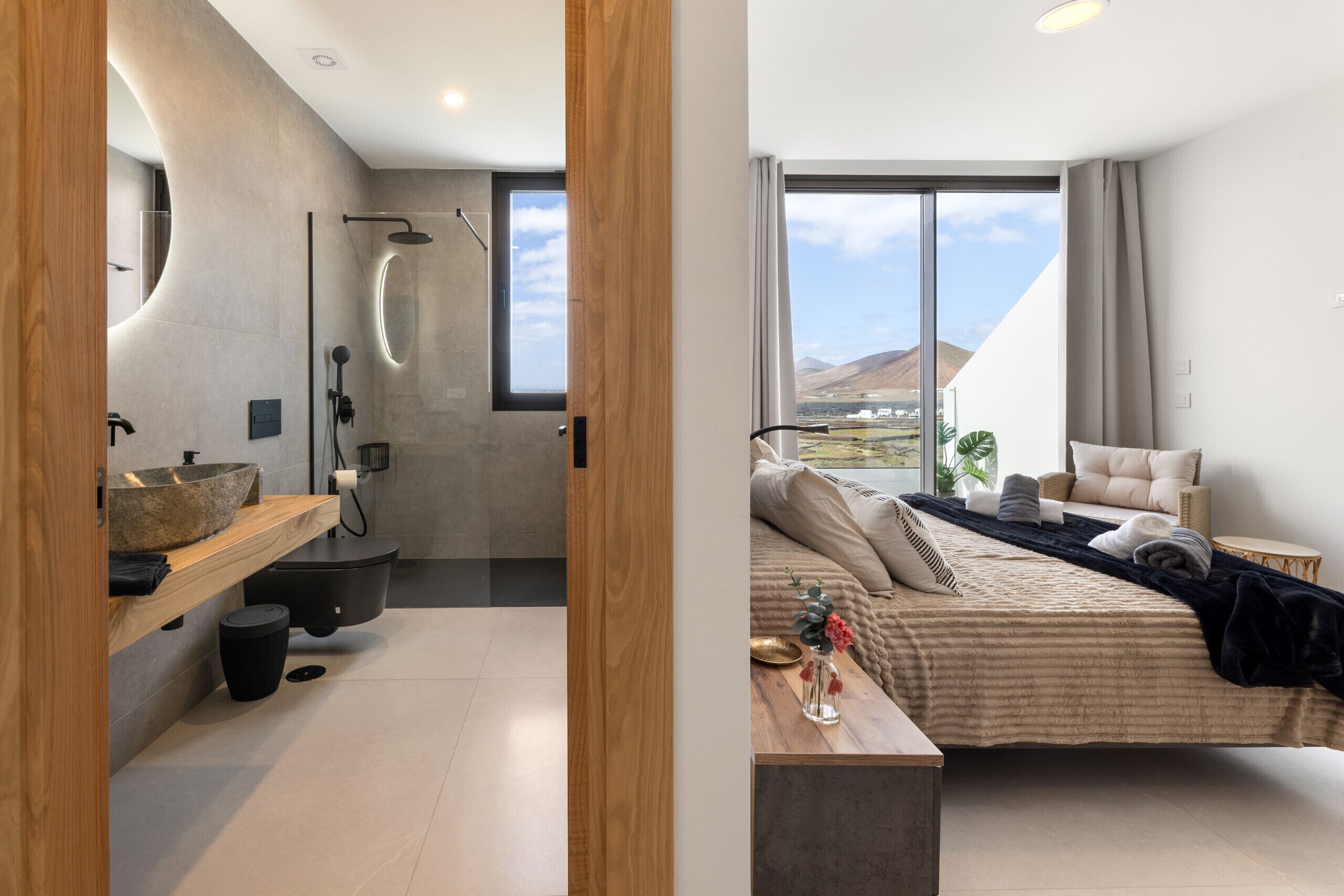 A modern bathroom with a large bathtub, a wooden vanity, and a large window.