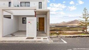 Un edificio moderno con fachada blanca, puerta de madera y vistas a un paisaje montañoso.