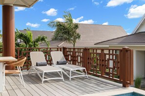 Eine Terrasse mit zwei Liegestühlen, einem Tisch und einem Pool.