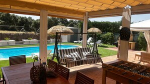 Un'area esterna coperta con piscina, sedie a sdraio, tavolo da calcio e bersaglio per freccette.