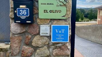Un muro in pietra con un cartello di casa in stile rustico, una cassetta delle lettere e un armadietto utenze.