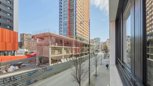 A high-rise building with a construction site in the foreground, a pedestrian walkway, and a clear sky. - CP Apartments Bilbao (Bilbao)