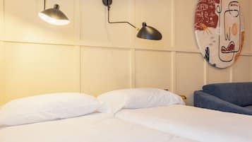 A hotel room with a bed, two wall-mounted lamps, and a wall decoration.