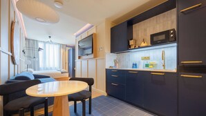 A modern kitchen with dark cabinets, a microwave, and a dining area with a table and chairs. - CP Apartments Bilbao (Bilbao)