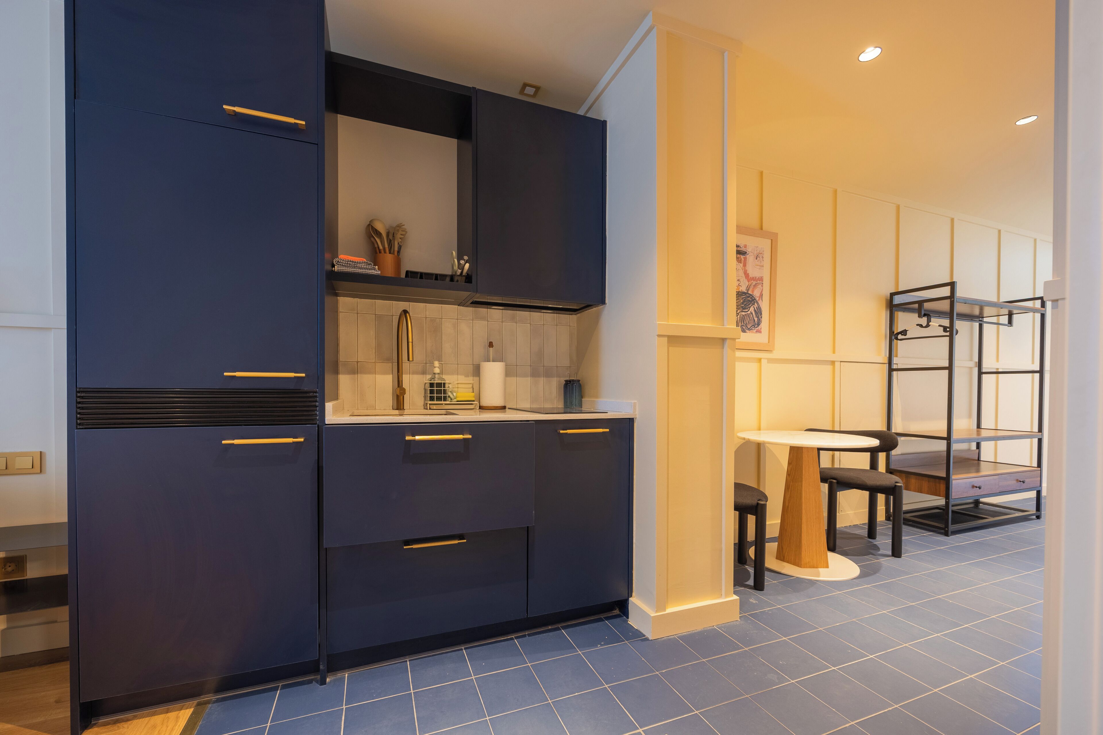 A modern kitchen with dark cabinetry, a white countertop, and a dining area with a table and chairs.