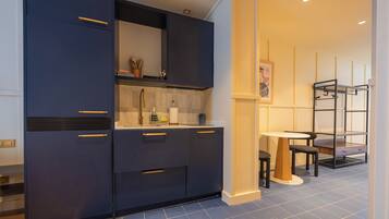 A modern kitchen with dark cabinetry, a white countertop, and a dining area with a table and chairs.