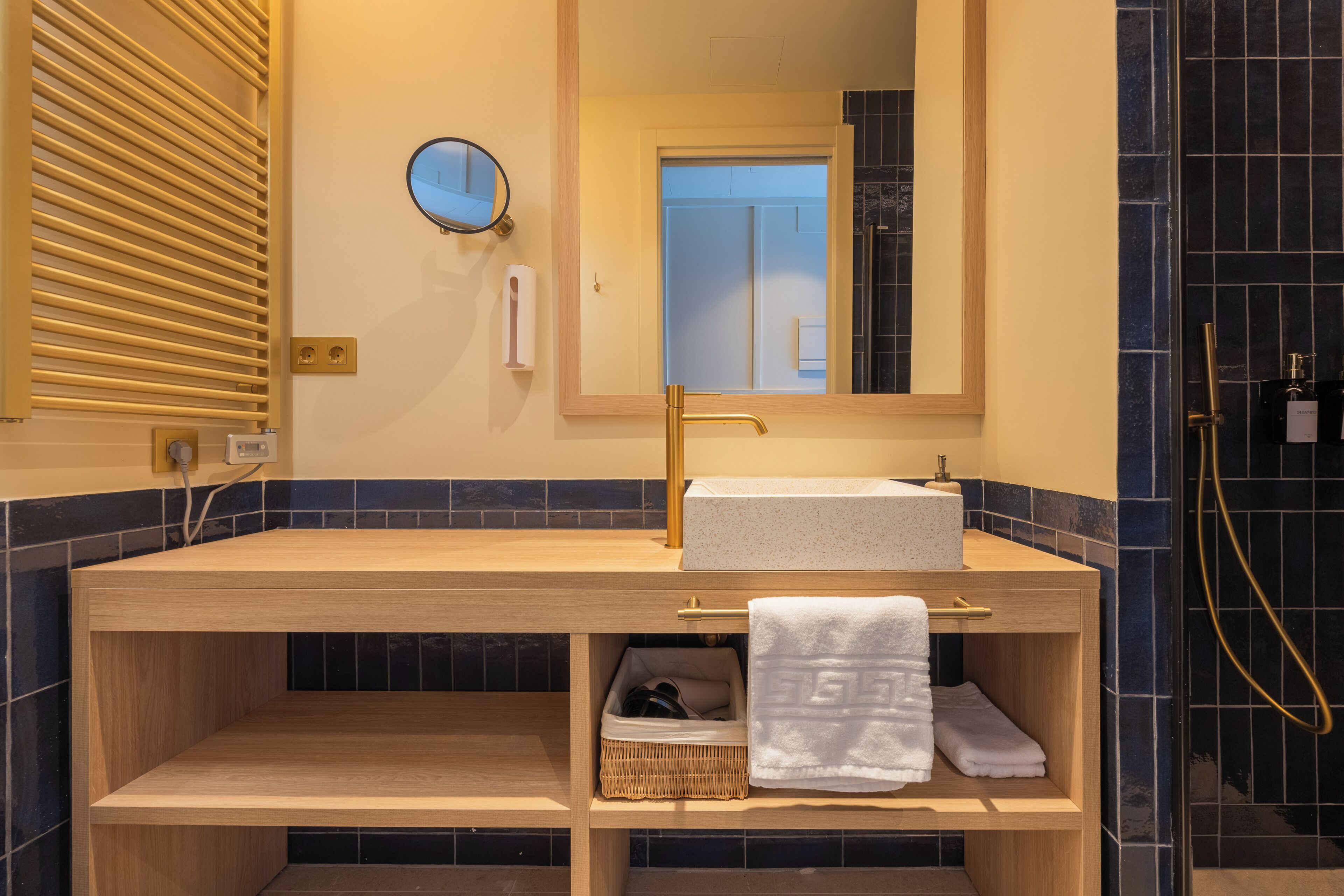 A bathroom with a wooden vanity, a mirror, a towel rack, and a shower area.