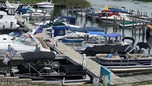 A marina with various boats docked, a wooden pier, and a forested hillside in the background. - 4BR house in Cheboygan with a game room and a private boat slip nearby (Cheboygan)