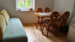 Une pièce avec un canapé vert, une table à manger en bois et des chaises.