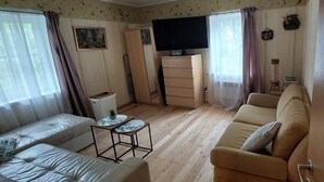 Un salon avec un canapé, une petite table, un téléviseur et un meuble.