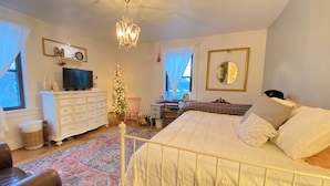 Ein Schlafzimmer mit Bett, Kommode, Fernseher, Weihnachtstanne und Spiegel.