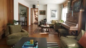 Ein Wohnzimmer mit einem Klavier, Sofas, einem Couchtisch und einer Treppe, die in einen anderen Raum führt.