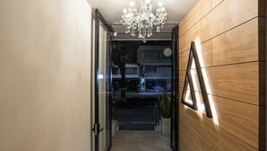 Un couloir orné d’un lustre, doté de boiseries et d’un tableau encadré accroché au mur.