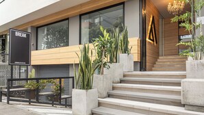 Un bâtiment moderne avec un escalier, une pancarte indiquant « PAUSE » et des plantes en pot.