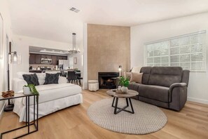 A modern living room with a sofa, a coffee table, and a fireplace. - 2BR Retreat: Pool, Tesla Charger, Near Attractions (Tempe)