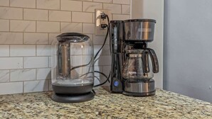 Une machine à café et une verseuse en verre sur un plan de travail de cuisine.