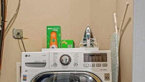 Un appareil combiné lave-linge et sèche-linge à chargement frontal, doté d’un panneau de commande, d’un câble d’alimentation et de compartiments à lessive situés sur le dessus.